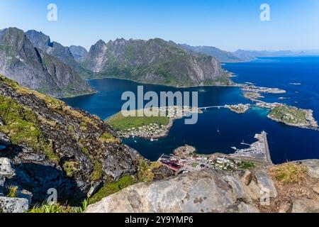 Vue panoramique sur les fjords norvégiens depuis une montagne, surplombant un village côtier et des eaux bleues calmes entourées de montagnes escarpées. Vue à rein Banque D'Images