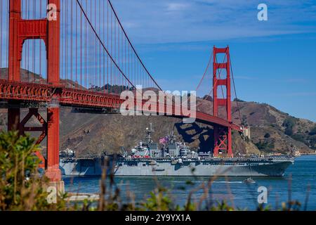 San Francisco, Californie, États-Unis. 6 octobre 2024. Le navire d'assaut amphibie de classe américaine USS Tripoli (LHA 7) transite sous le Golden Gate Bridge à l'appui de la San Francisco Fleet week (SFFW) 2024, le 6 octobre. SFFW, qui en est maintenant à sa 43e édition, est une célébration de service maritime honorée de temps qui permet aux citoyens de la région de la baie de constater les capacités maritimes d'aujourd'hui de première main. Près de 2 500 marins, Marines et gardiens de la côte présenteront leurs capacités et leur équipement, participeront à divers événements de service communautaire et profiteront de l’hospitalité de la région de la Baie pendant l’événement. (Crédit IM Banque D'Images