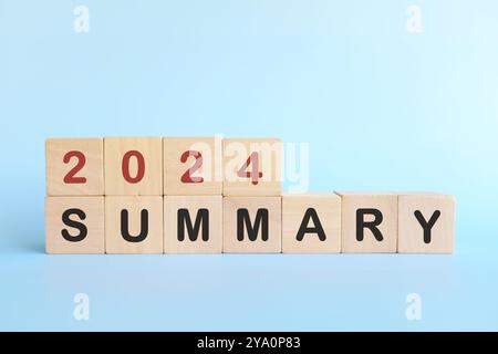Concept récapitulatif de fin d'année 2024. Typographie de blocs en bois sur fond bleu. Banque D'Images