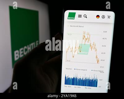 Dans cette illustration photo, une personne tient un téléphone portable avec la page Web de la société allemande de technologie de l'information Bechtle AG devant le logo. Banque D'Images