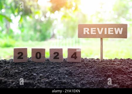 Examen de fin d'année 2024 et concept de résumé. Blocs en bois dans le coucher du soleil sombre sur fond naturel. Banque D'Images