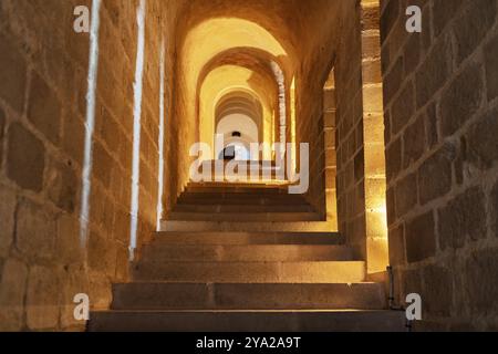 Escalier voûté en pierre avec éclairage chaleureux dans un cadre antique, le Mont-Saint-Michel Banque D'Images