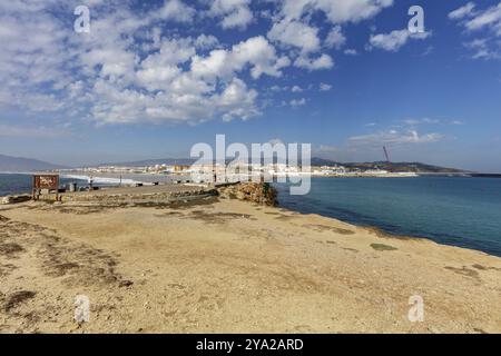 Paysage côtier avec vue sur la mer et une ville lointaine sous un ciel sans nuages, Tarifa Banque D'Images