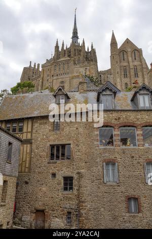 Vue sur les bâtiments du Mont Saint-Michel, dominés par des tours et des façades en pierre sous un ciel nuageux, le Mont-Saint-Michel Banque D'Images