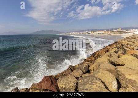 Côte rocheuse avec des vagues écrasantes et une vue panoramique sur la mer à la ville en arrière-plan, Tarifa Banque D'Images