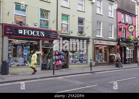 Scène de rue animée avec des gens marchant et des boutiques colorées le long de la rue, Tralee Banque D'Images