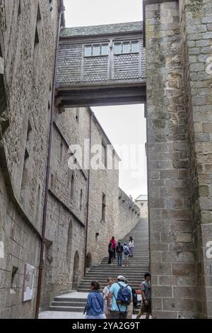 Les gens sur les marches entre les ruelles de pierre et les murs historiques d'un site médiéval, le Mont-Saint-Michel Banque D'Images