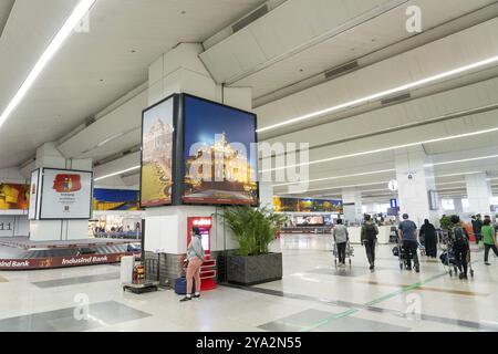 Delhi, Inde, le 30 mars 2023 : des personnes attendent aux tapis transporteurs de récupération des bagages dans la zone d'arrivée de l'aéroport international Indira Gandhi, en Asie Banque D'Images