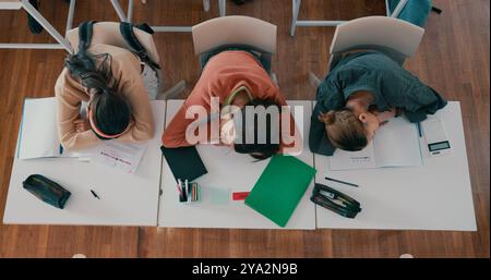 Fatigué, dormant et élèves sur le bureau en classe à l'école avec fatigue en leçon pour apprendre. Burnout, repos et groupe d'adolescents avec sieste pour Banque D'Images