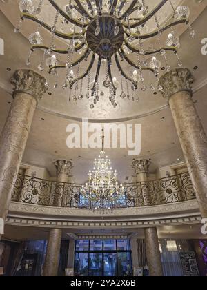 Intérieur opulent du hall avec de grands piliers ornés et de grands lustres suspendus au plafond détaillé. Cadre luxueux du hall d'entrée dégageant l'élégance Banque D'Images