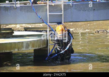 Plongeur grimpe dans le réservoir d'aération d'une station d'épuration Banque D'Images