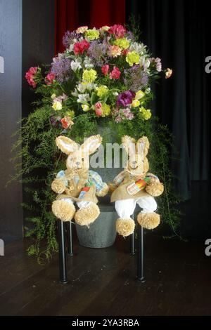 2 lapins de Pâques assis devant une belle décoration florale Banque D'Images