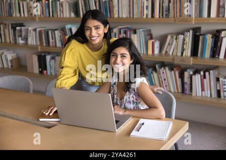 Joyeuses amies étudiantes indiennes jeunes adultes étudiant dans la bibliothèque Banque D'Images