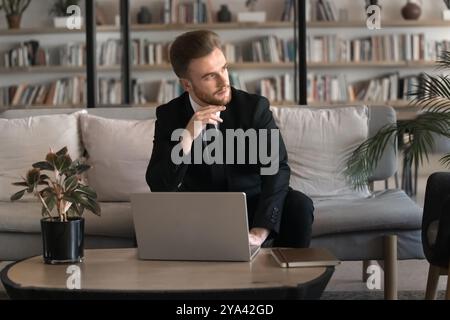 Homme professionnel sérieux réfléchi en costume formel à l'aide d'un ordinateur portable Banque D'Images