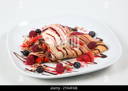 Crêpes (crêpe) avec baies mélangées, chocolat recouvert, fond blanc. Vue de dessus Banque D'Images