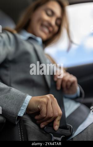 Jolie jeune femme d'affaires attachant la ceinture de sécurité dans la voiture sur la place du conducteur montrant la sécurité et la préparation Banque D'Images