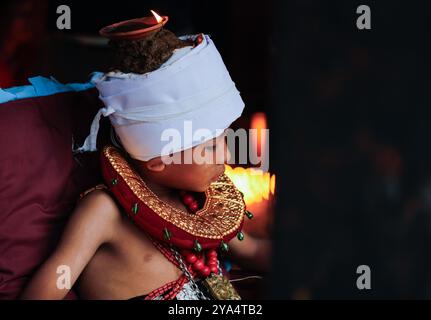 Bhaktapur, Népal. 12 octobre 2024. Un jeune dévot avec des lampes à huile allumées sur la tête et le corps prend part à la prière religieuse devant le temple Brahmayani pendant Durga Puja, le jour le plus propice du festival Dashain. Crédit : SOPA images Limited/Alamy Live News Banque D'Images