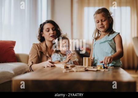 Mère s'engageant avec les filles dans le temps de jeu créatif à la maison Banque D'Images