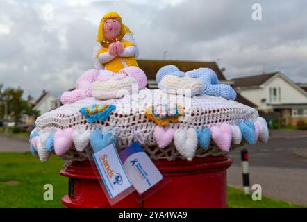 Poole, Dorset, Royaume-Uni. 12 octobre 2024. Un topper de boîte aux lettres tricoté apparaît sur une boîte aux lettres rouge à Poole, dans le Dorset, en reconnaissance de la semaine de sensibilisation à la perte de bébé (9-15 octobre) qui en est à sa 22e année, montrant son soutien aux familles touchées par la perte de bébé et se souvenant des bébés qui ne sont malheureusement plus avec nous. Crédit : Carolyn Jenkins/Alamy Live News Banque D'Images