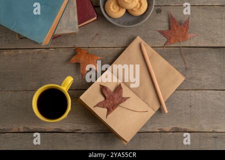 cahier vierge avec thème d'automne affiché sur une table en bois. feuilles séchées tombées et maquette de cahier vide sur fond ou surface en bois. vue de dessus co Banque D'Images