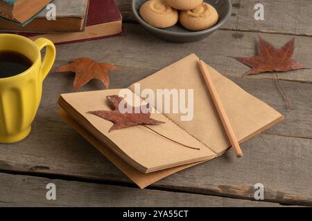 cahier vierge avec thème d'automne affiché sur une table en bois. feuilles séchées tombées et maquette de cahier vide sur fond ou surface en bois. vue latérale c Banque D'Images
