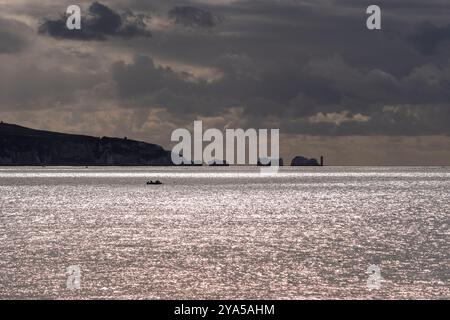 Needles point et phare sur l'île de Wight, silhouetté par la lumière vive sur la mer et les nuages sombres, Angleterre, Royaume-Uni, octobre Banque D'Images