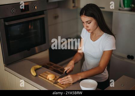 Jeune femme préparant des fruits frais dans un cadre de cuisine moderne Banque D'Images