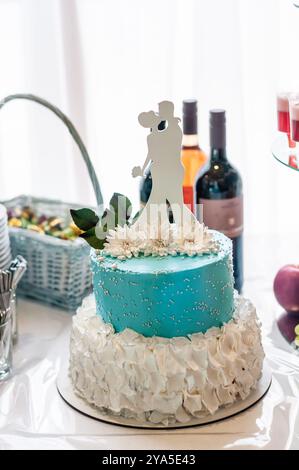 Elégant gâteau de mariage à deux niveaux orné d'un surmatelas Silhouette et de touches florales. Banque D'Images