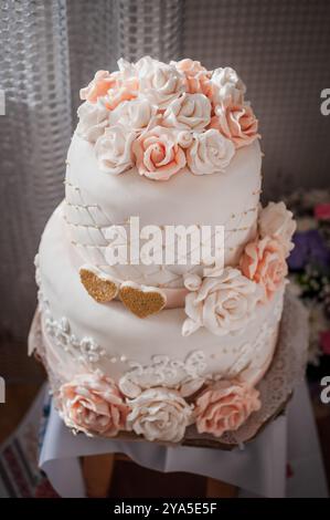 Elégant gâteau de mariage à deux niveaux orné de délicates roses de sucre. Banque D'Images