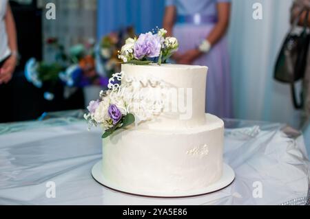 Elégant gâteau de mariage à deux niveaux orné de fleurs délicates. Banque D'Images