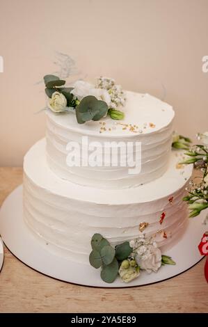 Elégant gâteau de mariage blanc à deux niveaux avec des accents floraux. Banque D'Images