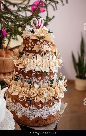 Elégant gâteau de célébration à trois niveaux orné de roses crème et de délicates accents de dentelle. Banque D'Images