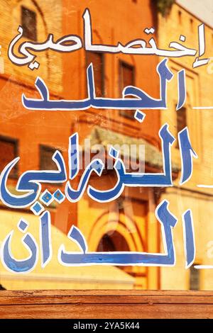Inscription en lettres arabes sur une fenêtre reflétant les bâtiments environnants Banque D'Images