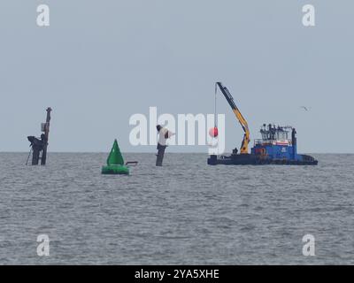 Sheerness, Kent, Royaume-Uni. 12 octobre 2024. Les travaux visant à rétablir un anneau de bouées de « danger » autour de l'épave du SS Richard Montgomery ont été entrepris dans la Tamise aujourd'hui par le navire ShakeDog. Les bouées distinctives rouge vif avec le mot « danger » écrit dessus avertissent les marins de ne pas entrer dans une zone d'exclusion en forme de losange de 250 m autour de l'épave, qui est surveillée 24/7 par les autorités en raison du naufrage du navire avec 1400 tonnes d'explosifs en 1944. Les 12 bouées rouges ont été retirées temporairement en novembre dernier pour aider à des travaux spéciaux d'arpentage. Crédit : James Bell/Alamy Live News Banque D'Images