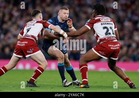 James Batchelor des Hull Kingston Rovers (au centre) en action avec le ballon sous la pression du Jai Field des Wigan Warriors (à gauche) et du Junior Nsemba des Wigan Warriors lors de la Grande finale de Betfred Super League à Old Trafford, Manchester. Date de la photo : samedi 12 octobre 2024. Banque D'Images