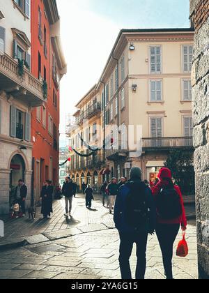 Une scène de rue animée à Monza, en Italie, avec des gens se promenant entre des bâtiments colorés. Les décorations festives sont suspendues au-dessus de la tête Banque D'Images