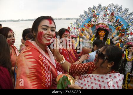 Kolkata, Inde. 12 octobre 2024. Les femmes marrées indiennes appliquent 'Sindur', ou poudre de vermillon, les unes sur les autres après avoir adoré une idole d'une déesse hindoue lors de l'immersion de la déesse Durga dans le fleuve Gange, ce qui marque la fin du festival Hindou Durga Puja. Le festival Durga Puja est le plus grand événement religieux pour les hindous bengalis, croyez que la déesse Durga symbolise le pouvoir et le triomphe du bien sur le mal. Le 12 octobre 2024 à Kolkata, Inde. (Photo de Dipa Chakraborty/ crédit : Eyepix Group/Alamy Live News Banque D'Images