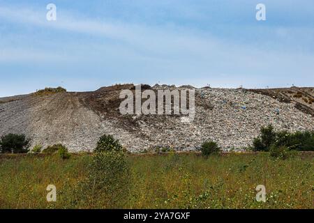 Un site d'enfouissement avec d'énormes tas de déchets et d'ordures, situé dans une zone naturelle. Cette image met en évidence la pollution environnementale et la gestion des déchets Banque D'Images