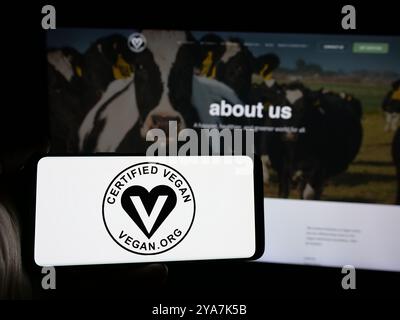 Personne tenant un smartphone avec le logo de l'organisation américaine Vegan Awareness Foundation sur l'écran en face du site Web. Concentrez-vous sur l'affichage du téléphone. Banque D'Images