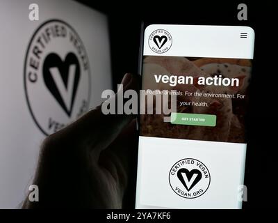 Personne tenant le téléphone portable avec la page Web de l'organisation américaine Vegan Awareness Foundation sur l'écran devant le logo. Concentrez-vous sur le centre de l'écran du téléphone. Banque D'Images