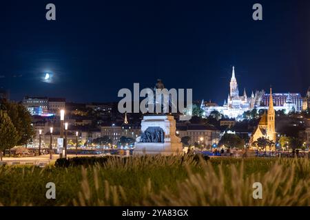 Budapest, Hongrie - 12 août 2024 : Statue du comte Gyula Andrássy la nuit. La lune et le bastion pêcheur sur le fond. Banque D'Images