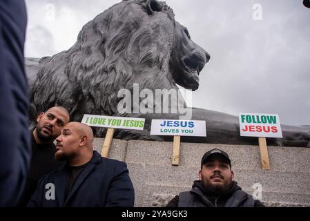 Londres, Royaume-Uni. 12 octobre 2024. Les fidèles ont placé leurs pancartes à côté de l'un des lions Landseer sur la place Trafalgar pendant la marche. Des centaines de chrétiens ont défilé dans le centre de Londres lors de l'événement appelé «Marche pour Jésus». C’est une procession de louanges dans les rues de la ville et célébrant la seigneurie de Jésus-Christ. Crédit : SOPA images Limited/Alamy Live News Banque D'Images