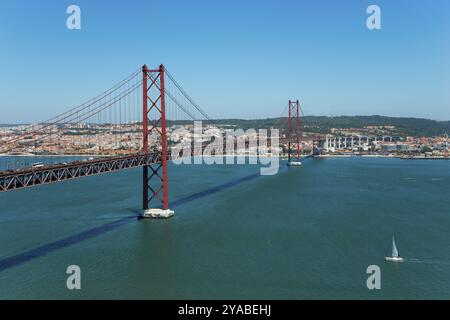 Vue panoramique d'un grand pont rouge sur une large rivière sous un ciel clair, Ponte 25 de Abril, 25 avril Pont, pont suspendu sur le Tage, double Banque D'Images