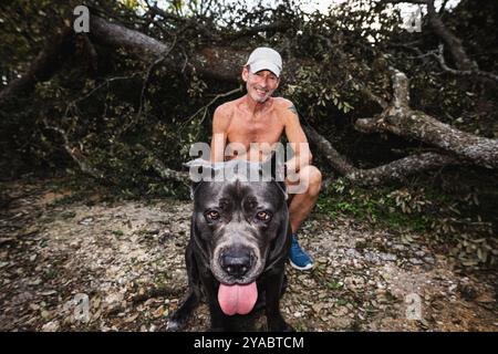 Dade City, Floride, États-Unis. 12 octobre 2024. Tommy et son chien Athena prennent un portrait devant leur maison battue dans la Sawmill Camping Resort Co-op (crédit image : © Dave Decker/ZUMA Press Wire) USAGE ÉDITORIAL SEULEMENT! Non destiné à UN USAGE commercial ! Banque D'Images