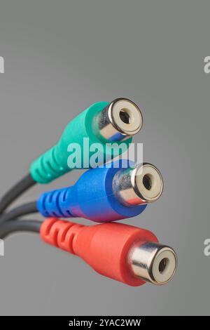 gros plan de trois prises ou connecteurs av isolés sur fond gris, fiches rouges, bleues et vertes vers d'anciens téléviseurs ou caméscopes utilisant des connecteurs rca Banque D'Images