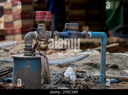 Un compteur d'eau est solidement fixé à un tuyau qui est encastré dans le sol Banque D'Images