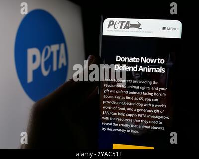 Personne tenant smartphone avec page web de personnes pour le traitement éthique des animaux (PETA) sur écran.. Concentrez-vous sur le centre de l'écran du téléphone. Banque D'Images