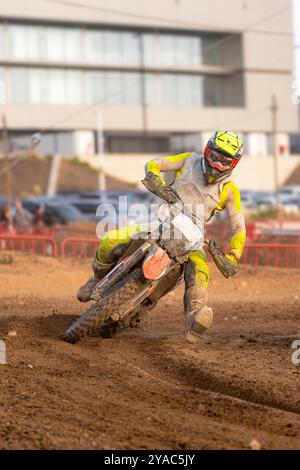 Pilote de motocross en action tournant et pliant sa moto avec sa jambe tendue pour maintenir l'équilibre dans un virage serré sur terrain mouillé pendant un o Banque D'Images