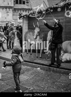 Un petit garçon qui fait éclater une bulle pendant Noël à Milan, en Italie Banque D'Images