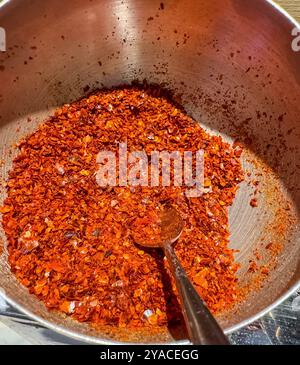 Épice aromatique. Flocons de piment rouge dans un bol, une cuillère et des gousses sur une table en bois. Photo de haute qualité Banque D'Images